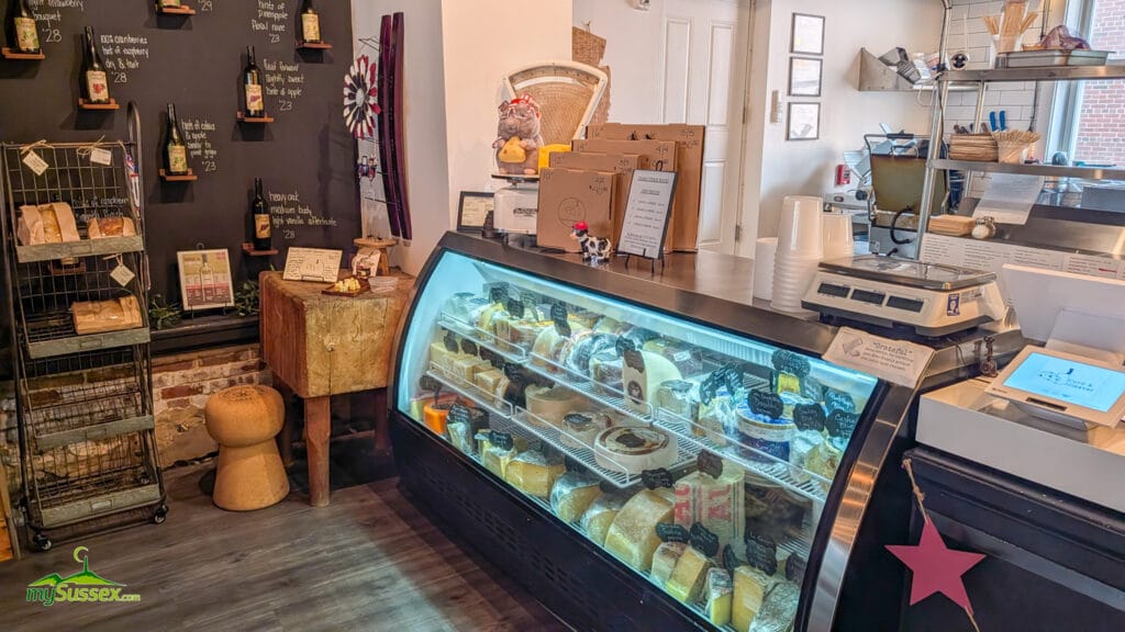 Artisan cheeses displayed in the refrigerated cheese case inside Curd & Cleaver in Newton, New Jersey.