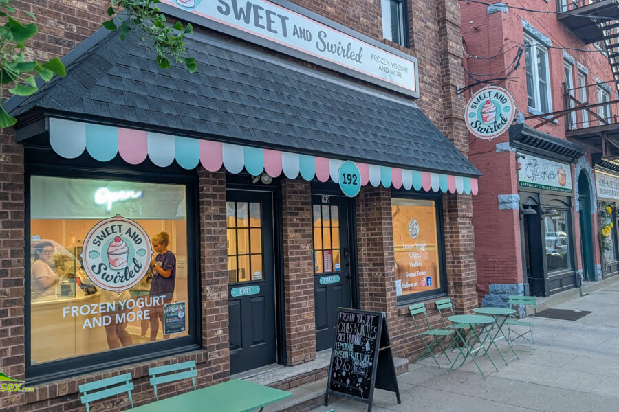 Sweet and Swirled storefront on a brick street in Newton with turquoise scalloped awning and matching outdoor seating.