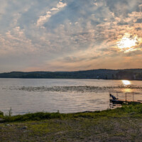 A teenager tosses pebbles into Swartswood Lake from the campers’ boat launch dock at sunset.